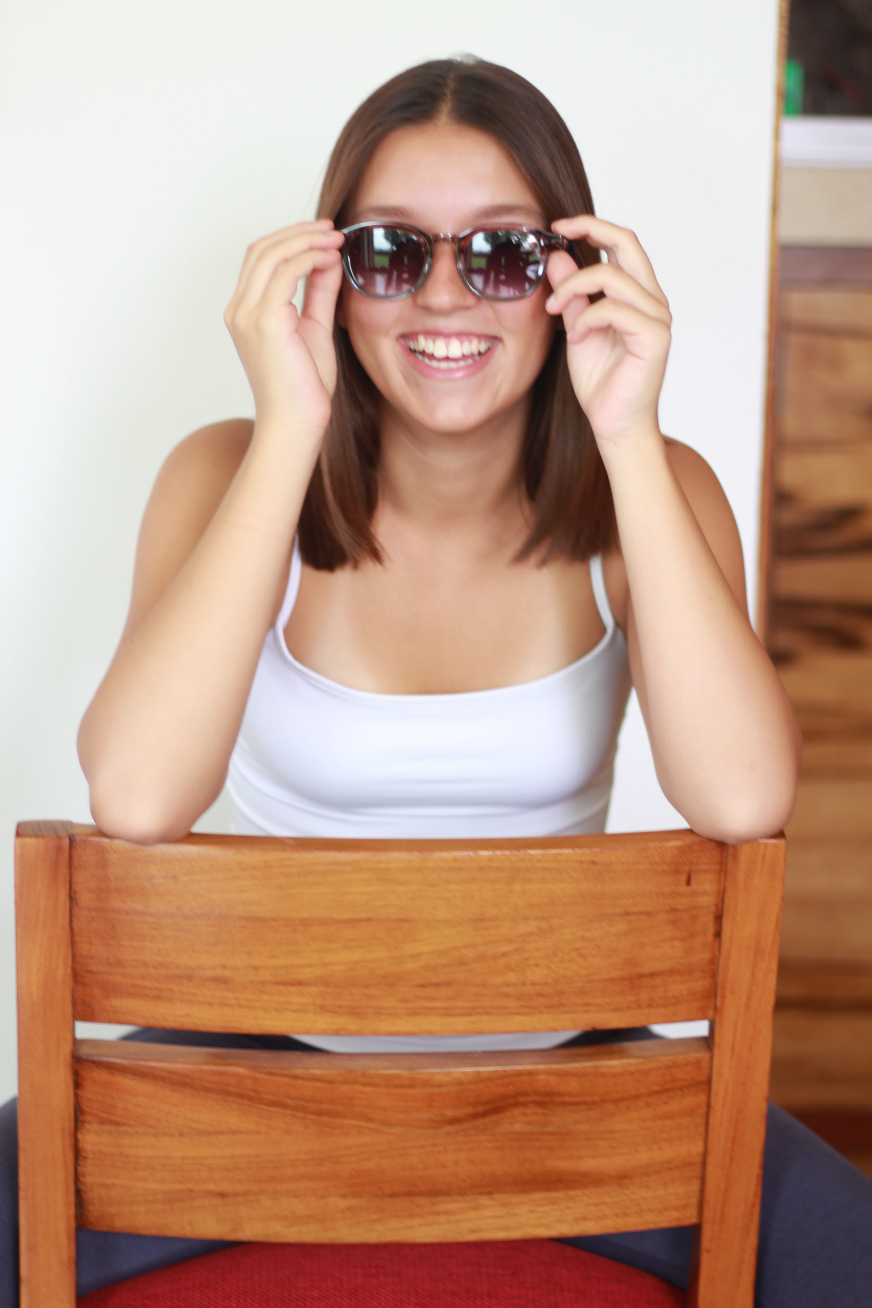 Model smiling in OPHRA round sunglasses, seated portrait