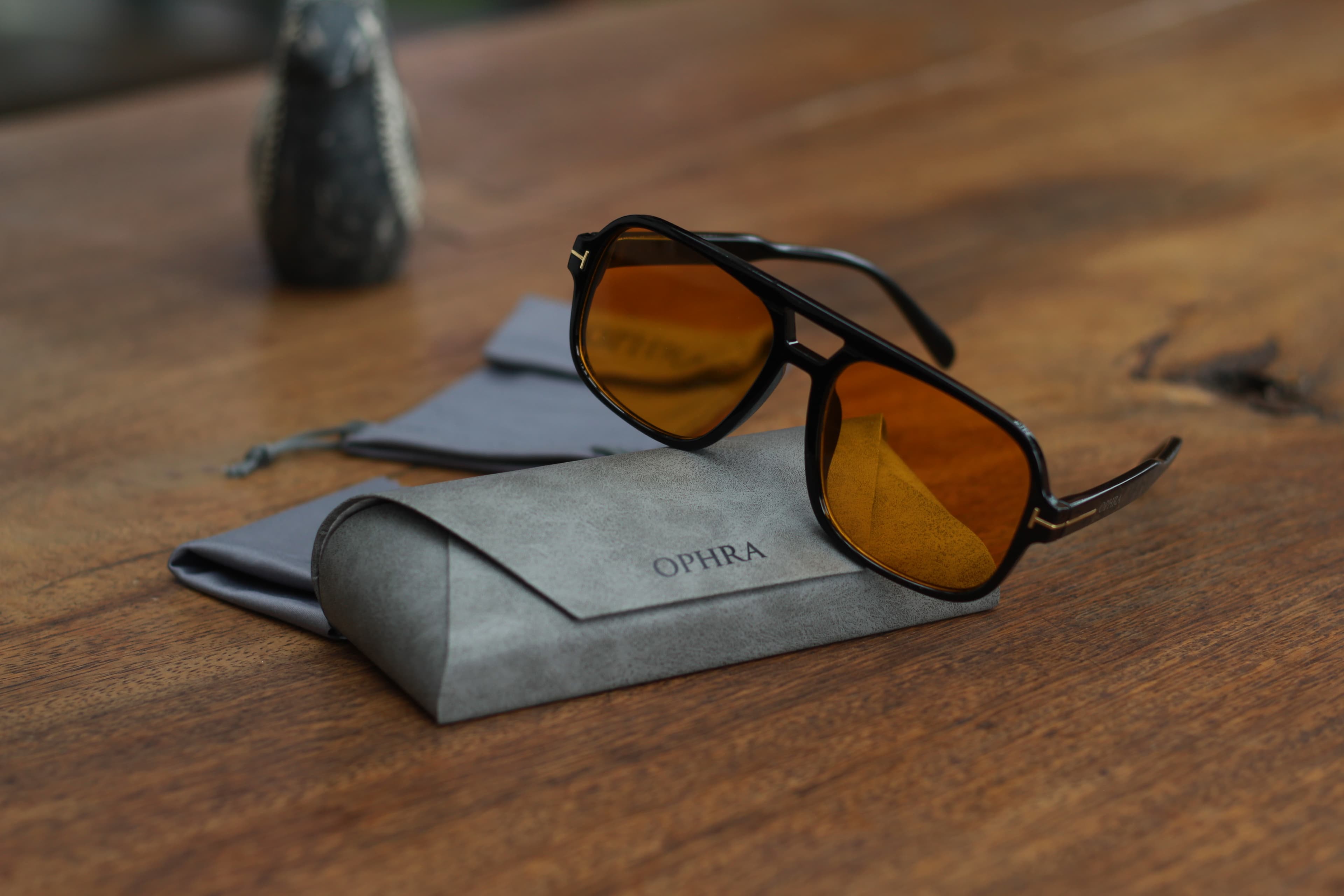 OPHRA amber aviator sunglasses resting on a suede pouch