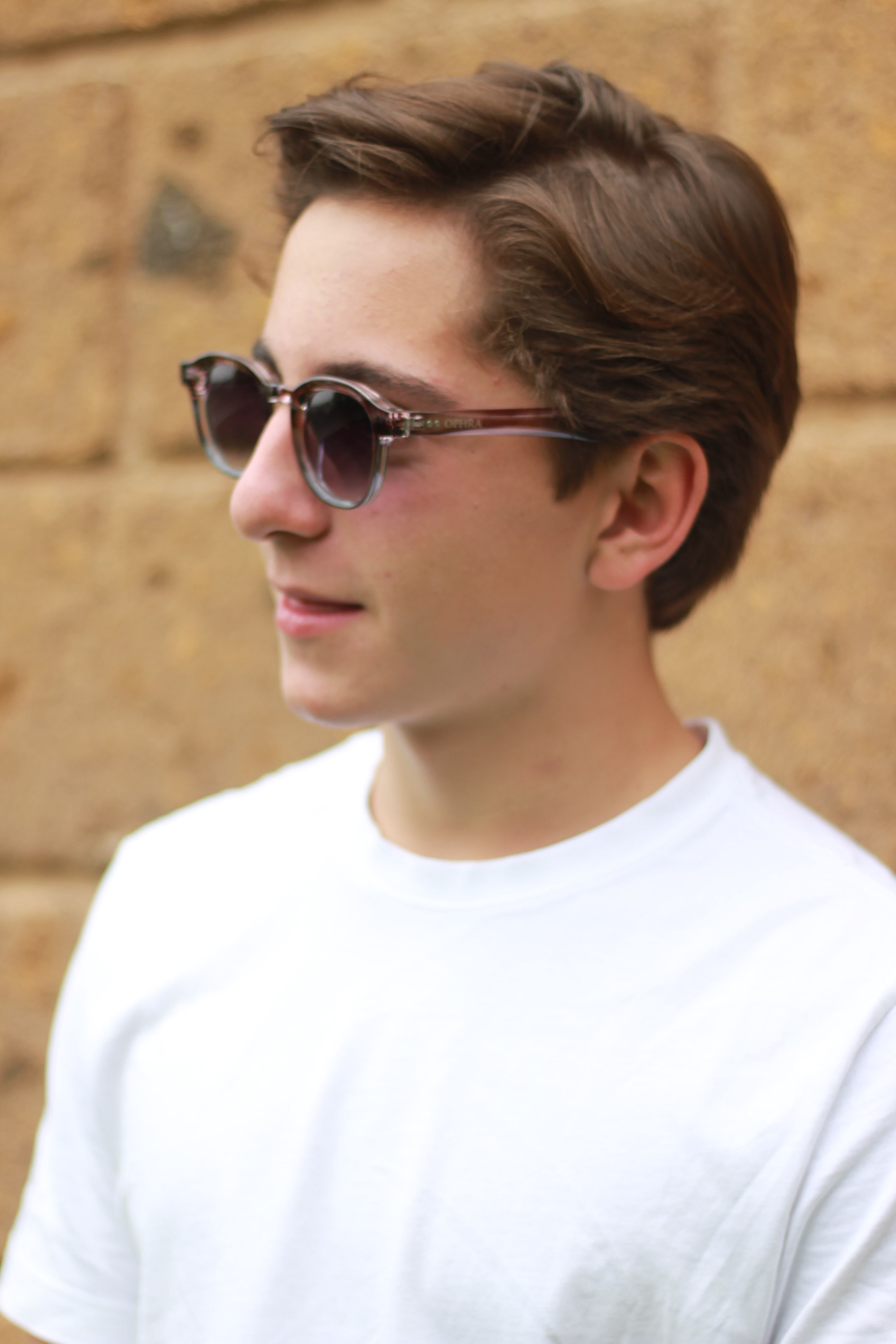 Model in OPHRA round sunglasses against a brick wall