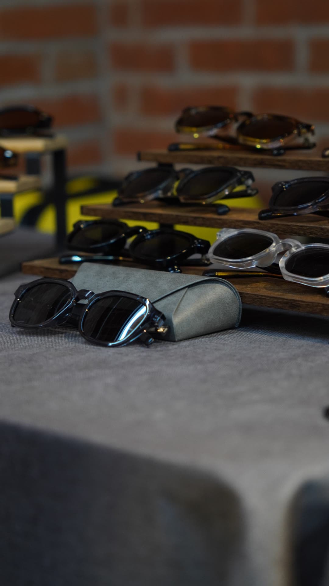 OPHRA sunglasses arranged on a tiered wooden display with a suede case